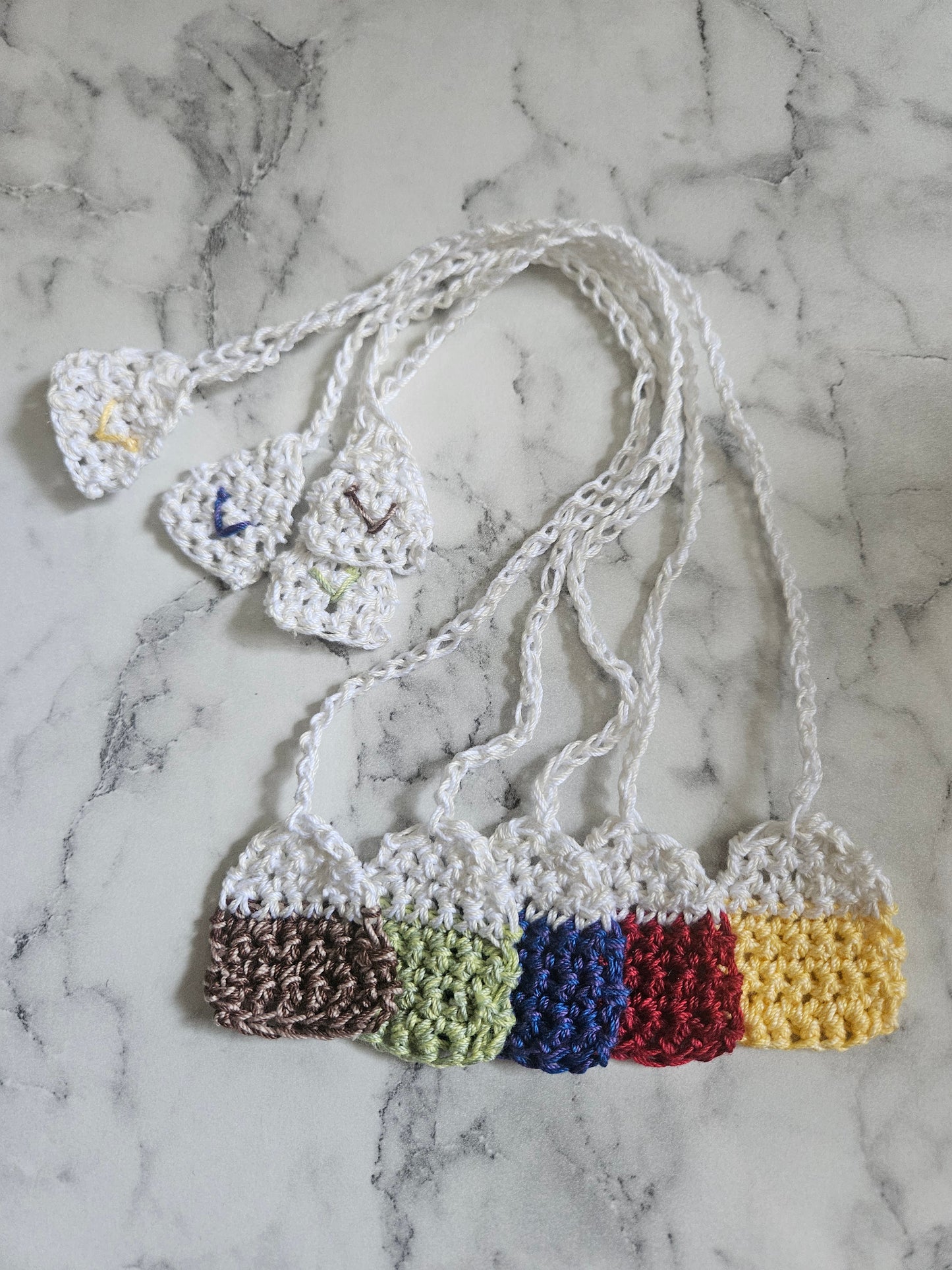 a complete set of crochet tea bag bookmarks in five different colours, with a signature "V" stitch on the tea bag end.